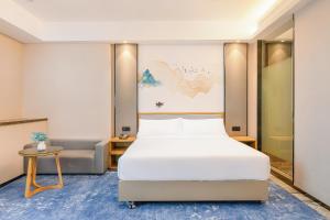 a hotel room with a bed and a chair at Licheng Langyue Hotel - Huizhou Huicheng Shuikou Branch in Huizhou