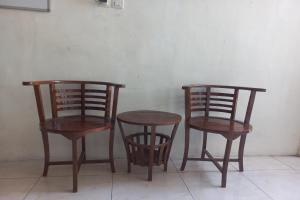 twee houten stoelen en een tafel en twee stoelen bij SPOT ON 93539 Juan Guest House in Purwokerto