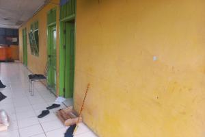 une chambre avec un mur jaune et un balai dans l'établissement SPOT ON 93539 Juan Guest House, à Purwokerto