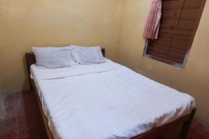 een slaapkamer met een bed met witte lakens en een raam bij SPOT ON 93539 Juan Guest House in Purwokerto