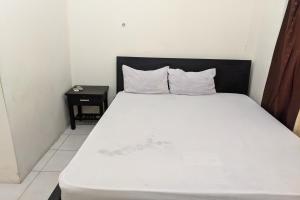 ein Schlafzimmer mit einem weißen Bett mit einem schwarzen Kopfteil in der Unterkunft OYO 93521 Wisma Flamboyan in Rantau