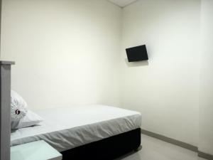 Dieses weiße Zimmer verfügt über ein Bett und einen TV an der Wand. in der Unterkunft OYO 93538 Millow Kost in Parepare