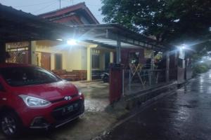 een rode auto geparkeerd voor een huis 's nachts bij SPOT ON 93542 Suripah Kostel Syariah in Banyumas