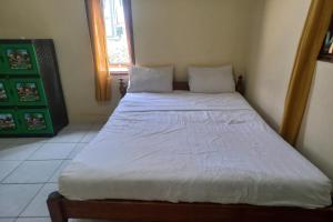a bedroom with a bed with white sheets and a window at SPOT ON 93542 Suripah Kostel Syariah in Banyumas
