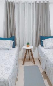a room with two beds and a table with a plant on it at Apartamento para locação em Itajai SC in Itajaí