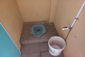 a small bathroom with a blue toilet and a bucket at SPOT ON 93542 Suripah Kostel Syariah in Banyumas