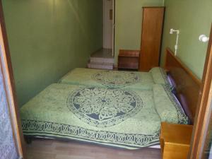 two beds in a room with green walls at Hotel du Berry in Perpignan