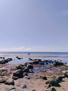 two people walking on a beach with rocks at A Villas Resort & Restaurant in Zamboanguita