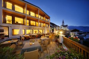 ein Restaurant mit Tischen und Stühlen auf einem Balkon in der Unterkunft Hotel Sonne in Stilfs