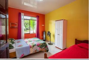 a bedroom with orange walls and a bed and a window at Yellow House in Quepos