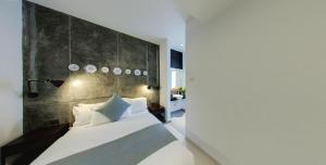 a bedroom with a white bed with a concrete wall at Modern Cave Boutique Stay in Melaka