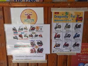 Una señal para una tienda de motos con carteles. en Pai Forest Resort, en Pai