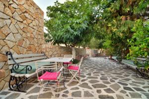 a patio with tables and chairs and a stone wall at Hotel Villa Marie in Sivota