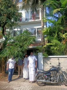 un grupo de personas de pie fuera de un edificio con una motocicleta en Adams Wood House Ayurveda Homestay Kochi, en Kochi