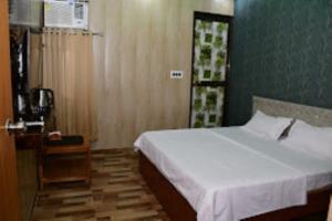 um quarto com uma cama branca e uma parede azul em Renu Paradise , Ayodhya em Ayodhya