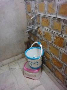 a bucket in the corner of a bathroom with a tap at Robin Desert Safari Camp in Jaisalmer
