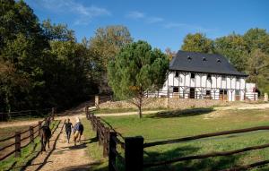 eine Gruppe von Menschen, die vor einem weißen Haus einen Pfad entlang gehen in der Unterkunft Cabane de La Mésange in Auriac-du-Périgord