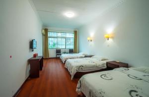 um quarto de hotel com três camas e uma janela em 张家界大庸家民宿DYJ Hostel em Zhangjiajie