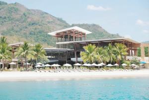 a resort on the beach with chairs and umbrellas at The Beach Suites at Pico De Loro in Nasugbu
