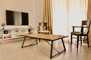 a living room with a table and chairs and a tv at Enkai Farmhouse near Ol-Pejeta Nanyuki in Nanyuki