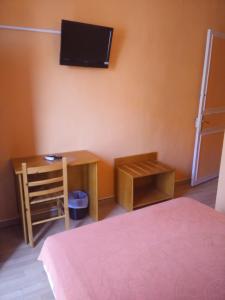 1 dormitorio con escritorio y TV en la pared en Hotel du Berry en Perpiñán