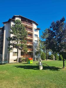 a building in a park with a statue in the grass at Nikol 3 SPA CLUB BOR in Velingrad
