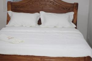 Cama con sábanas y almohadas blancas en Faradel Motel en Fomboni