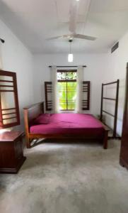 sypialnia z łóżkiem z fioletową pościelą i oknem w obiekcie Terance Bungalow w mieście Kosgoda