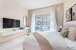 a white bedroom with a large bed and a window at Comfortable Studio at Lago Vista A Dubai Production City by Deluxe Holiday Homes in Dubai