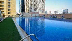a large swimming pool with blue chairs and buildings at Comfortable Studio at Lago Vista A Dubai Production City by Deluxe Holiday Homes in Dubai