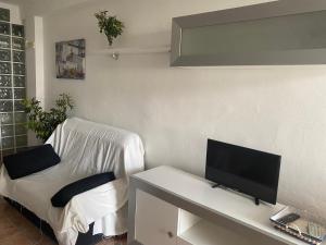 a living room with a tv and a white couch at ESTUDIO EN SANJOSE A 50 M DE LA PLAYA in San José