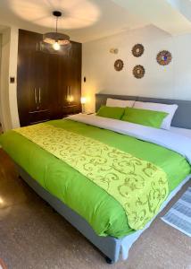 a bedroom with a large bed with green sheets at Cusco Magico 2 - Aparthotel Condominio Las Torres Kayser II in Cusco