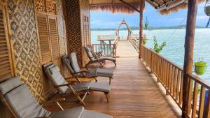 une terrasse couverte d'une maison avec des chaises sur l'eau dans l'établissement Kelong Pancing Madu Tiga, à Tanjung Pinang