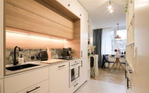a kitchen with white cabinets and a sink and a table at ECRU Designer Studio with Bedroom near Old Town WWA56 in Warsaw
