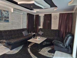 sala de estar con sofás de cuero negro y mesa en Apartman Gold en Tuzla