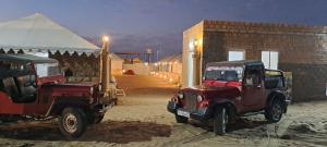 two red jeeps parked next to a building at Robin Desert Safari Camp in Jaisalmer