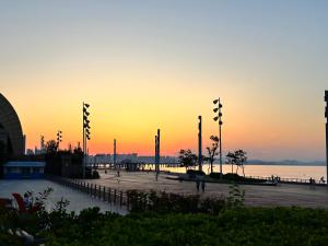 a sunset over a beach with a pier and the ocean at Yantai Marriott Hotel in Yantai +42 photos