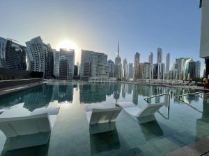 una piscina con due sedie bianche e lo skyline della città di Esclusive 1BR full Burj Khalifa View a Dubai