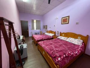 duas camas num quarto com paredes roxas em GO Bill B&B em Xinyi