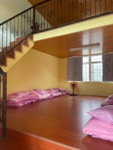 um quarto com almofadas cor-de-rosa alinhadas sob uma escada em GO Bill B&B em Xinyi