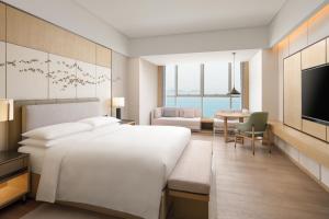 a bedroom with a large white bed and a living room at Yantai Marriott Hotel in Yantai
