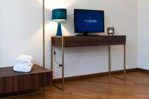 a room with a tv on a stand with a lamp at The Seven Residence in Genova