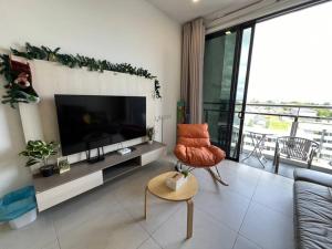 ein Wohnzimmer mit einem TV und einem Stuhl in der Unterkunft LV Homestay @ Gala Residence in Kuching