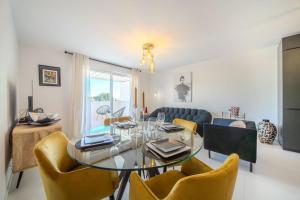 comedor con mesa de cristal y sillas amarillas en Le Square d'Evan - Appartement de Standing - Grande Terrasse Extérieure - Climatisation, en Saint-Aunès