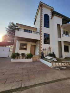 a large white house with a driveway in front of it at THE PERFECT STAYS: SUPREME BLISS VILLA in Lonavala