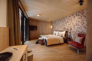 a bedroom with a bed and a red chair at Boutique Hotel Das Rivus in Leogang