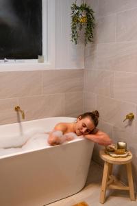a woman laying in a bath tub in a bathroom at Owl+Oak in Castlemaine