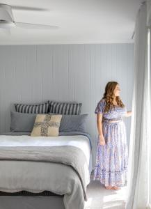 a woman in a blue dress is looking out a window at Owl+Oak in Castlemaine