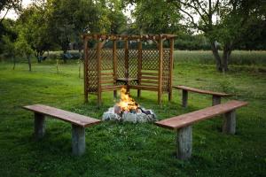 two benches sitting next to a fire in a park at RanczoLatyczyn 