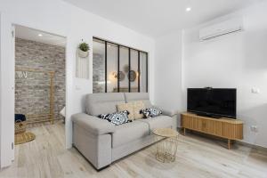 uma sala de estar com um sofá e uma televisão de ecrã plano em Agua Viva Mar em Málaga